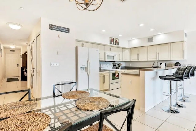 19811 Gulf Blvd Unit 102, Indian Shores, FL 33785 - kitchen with cream cabinetry, light tile patterned flooring, white appliances, and washer / clothes dryer