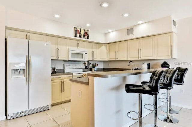 19811 Gulf Blvd Unit 102, Indian Shores, FL 33785 - kitchen featuring light tile patterned floors, white appliances, a breakfast bar area, and cream cabinets