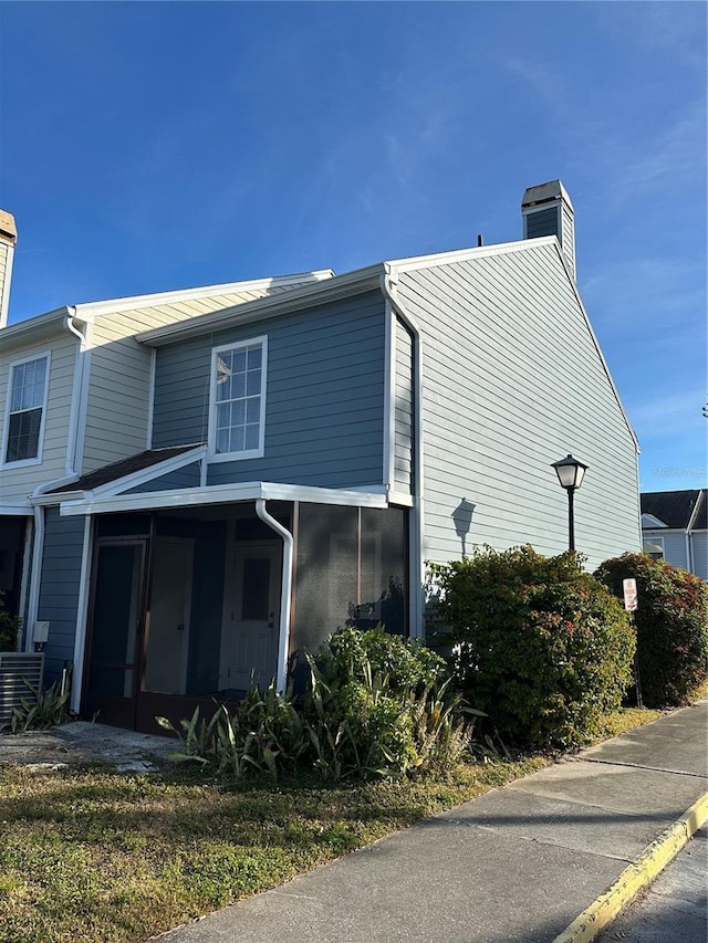 view of side of property featuring a sunroom and cooling unit