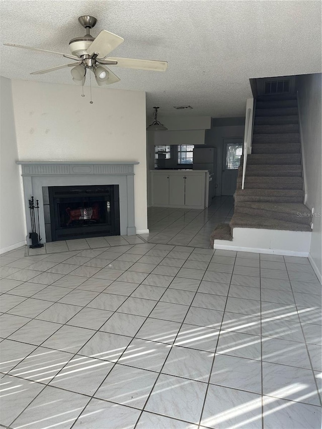 unfurnished living room featuring ceiling fan, a fireplace, and a textured ceiling