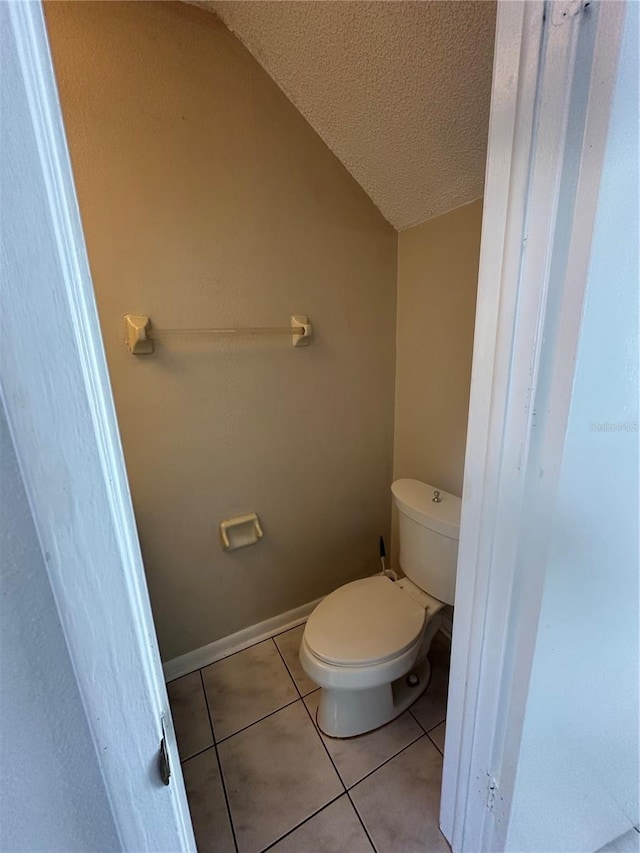 bathroom with tile patterned flooring, a textured ceiling, toilet, and vaulted ceiling