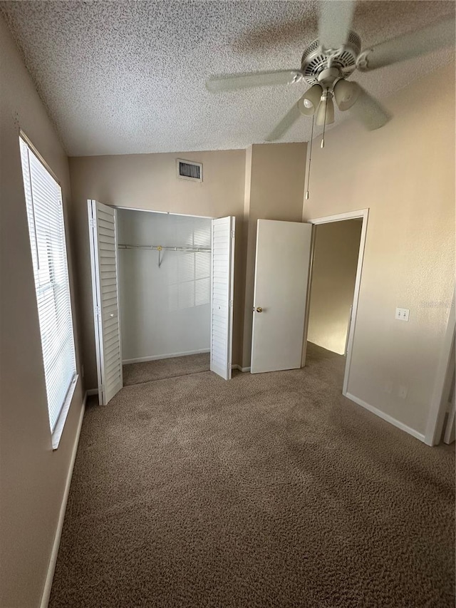 unfurnished bedroom with ceiling fan, a closet, carpet floors, and vaulted ceiling