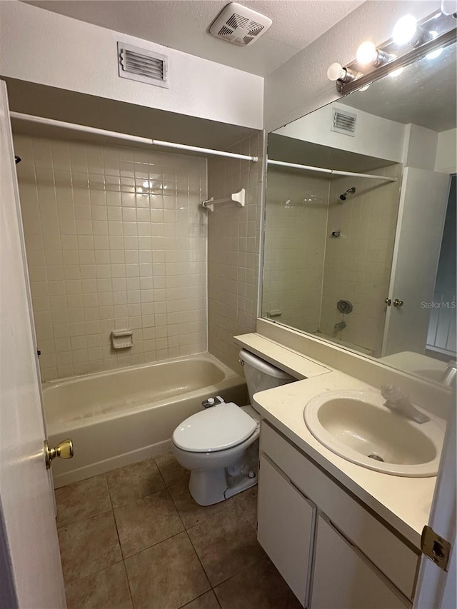 full bathroom with vanity, tile patterned flooring, tiled shower / bath combo, toilet, and a textured ceiling