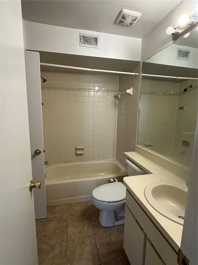 full bathroom featuring vanity, tile patterned flooring, tiled shower / bath combo, toilet, and a textured ceiling