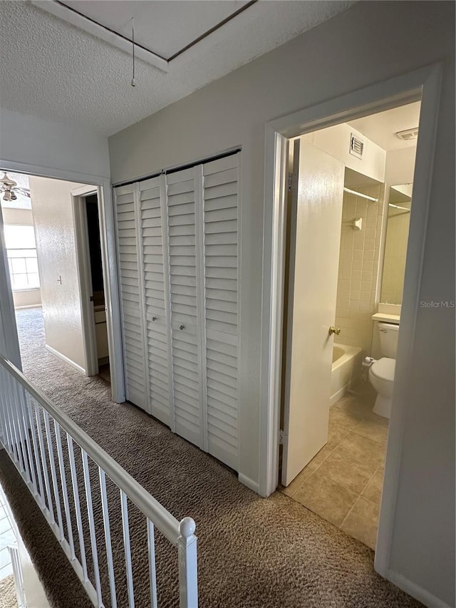 corridor with a textured ceiling and carpet floors