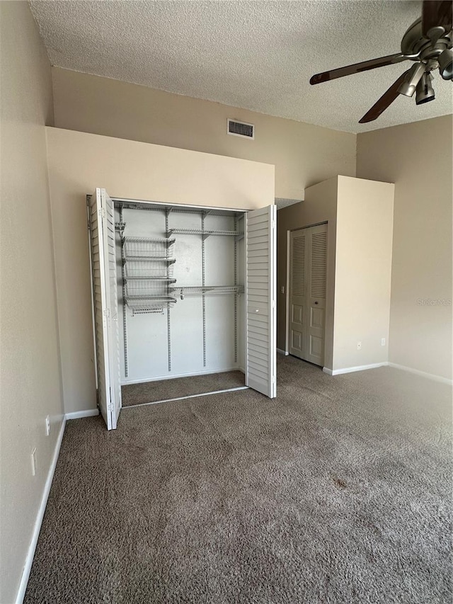 unfurnished bedroom featuring ceiling fan, a textured ceiling, and dark colored carpet