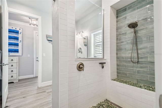 bathroom with a tile shower and hardwood / wood-style flooring