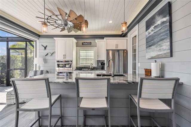 kitchen featuring decorative light fixtures, stainless steel fridge, a breakfast bar area, and dark stone counters