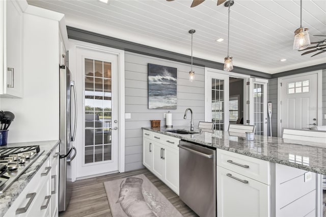 kitchen with sink, white cabinets, decorative light fixtures, and appliances with stainless steel finishes