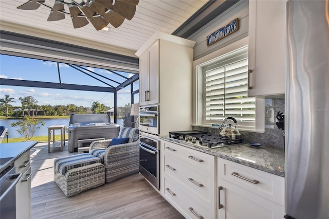 kitchen featuring a healthy amount of sunlight, white cabinetry, a water view, and stainless steel appliances