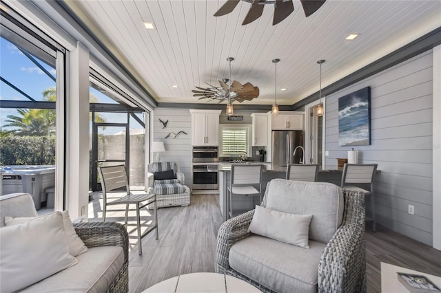 living room featuring hardwood / wood-style floors, ceiling fan, wooden ceiling, and wooden walls