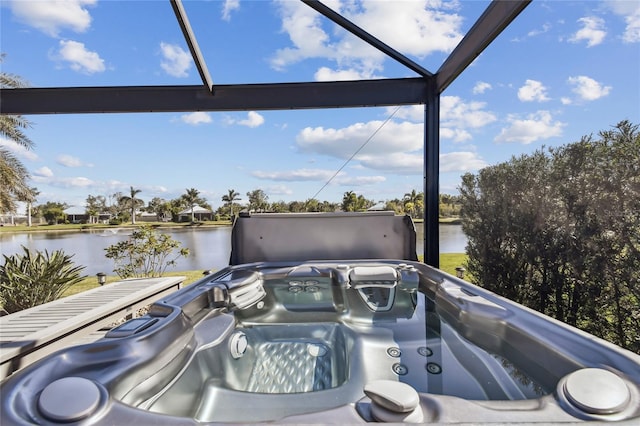 exterior space featuring glass enclosure, a water view, and a hot tub