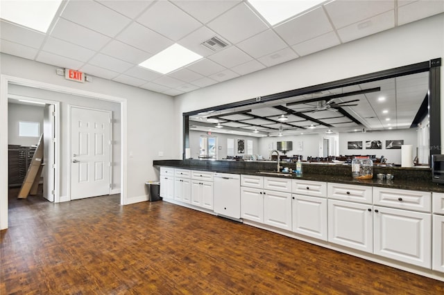 kitchen with white cabinets, dark hardwood / wood-style floors, dark stone countertops, and sink