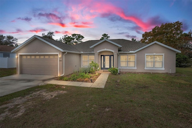 ranch-style home featuring a garage and a lawn