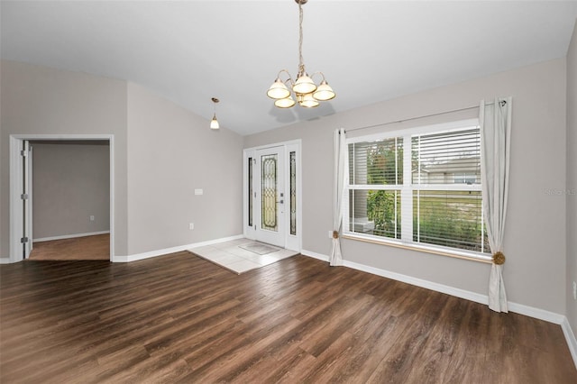 empty room with hardwood / wood-style floors, a notable chandelier, french doors, and vaulted ceiling