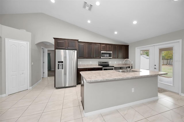 kitchen featuring lofted ceiling, french doors, sink, an island with sink, and stainless steel appliances