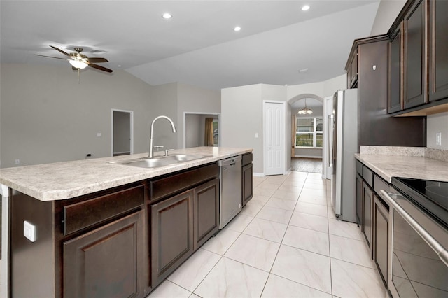 kitchen featuring appliances with stainless steel finishes, ceiling fan with notable chandelier, vaulted ceiling, sink, and a center island with sink