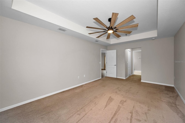 unfurnished bedroom featuring a raised ceiling, ceiling fan, and carpet