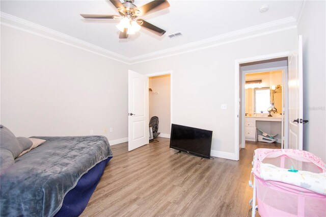 bedroom with a spacious closet, ceiling fan, light wood-type flooring, and ornamental molding