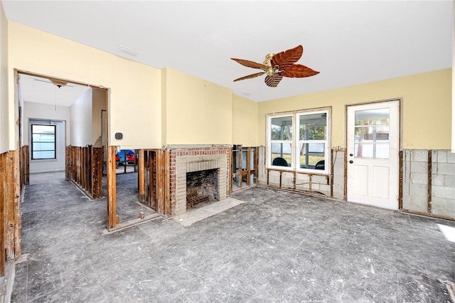 unfurnished living room featuring a wealth of natural light, a fireplace, and ceiling fan