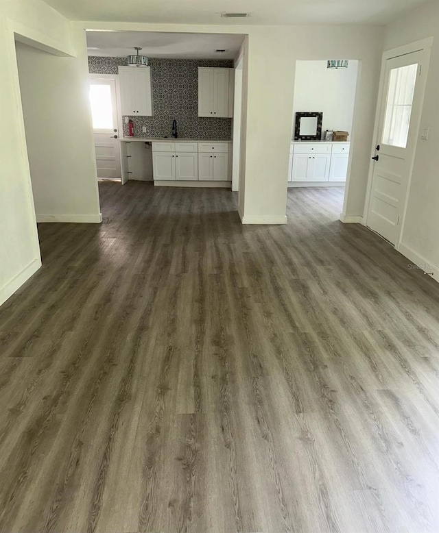 unfurnished living room with dark hardwood / wood-style floors, plenty of natural light, and sink