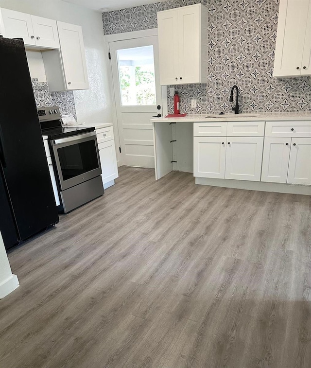 kitchen with light hardwood / wood-style floors, white cabinetry, stainless steel electric range oven, and sink