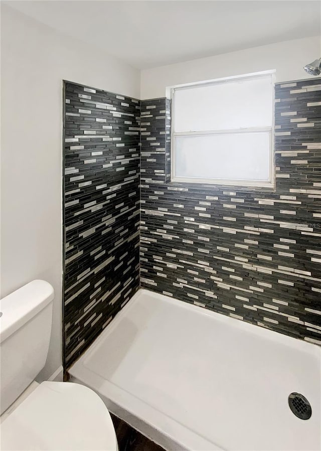 bathroom featuring toilet and tiled shower