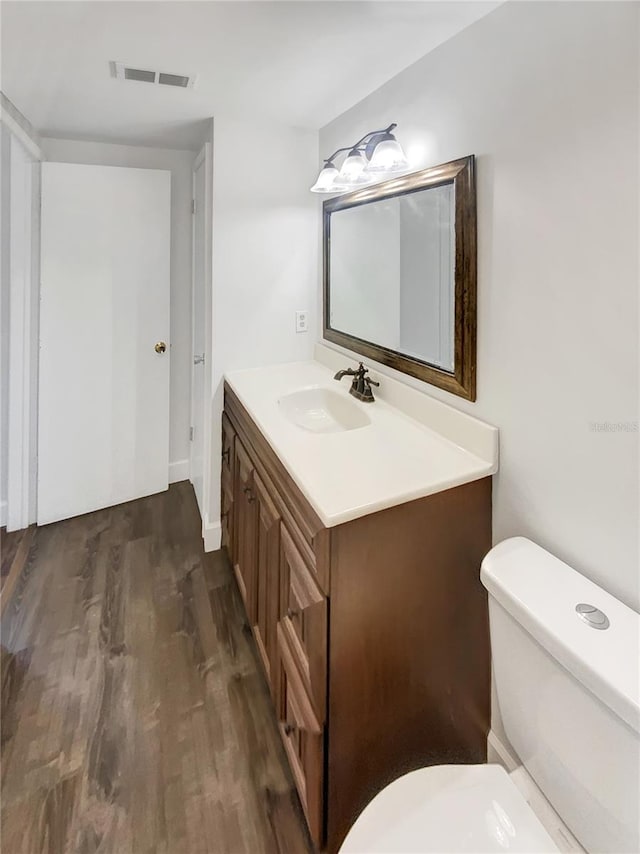 bathroom with hardwood / wood-style floors, vanity, and toilet