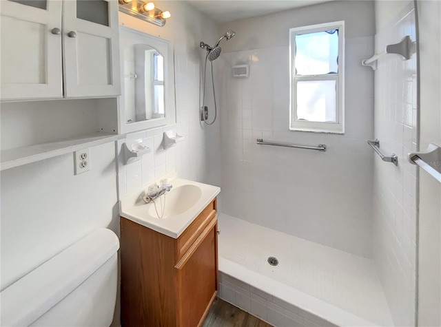 bathroom featuring decorative backsplash, a tile shower, vanity, wood-type flooring, and toilet