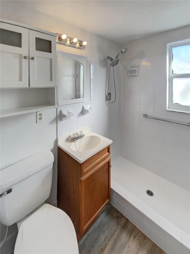 bathroom featuring hardwood / wood-style floors, vanity, toilet, and tiled shower