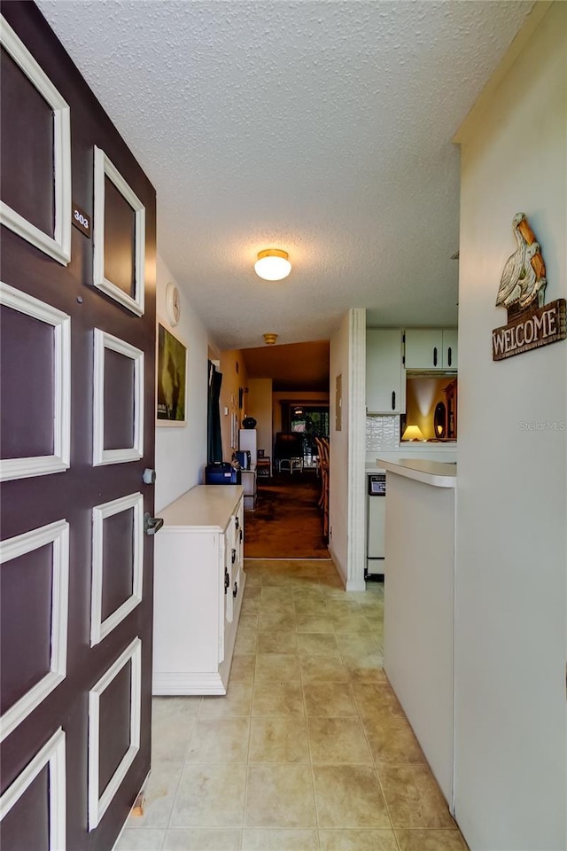 corridor featuring light tile patterned floors and a textured ceiling