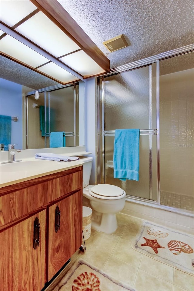 bathroom with vanity, a shower with door, tile patterned floors, toilet, and a textured ceiling