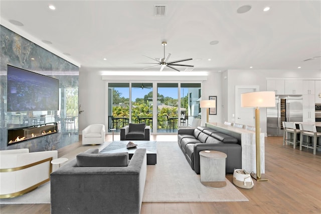 living room featuring ceiling fan, a fireplace, and light hardwood / wood-style floors