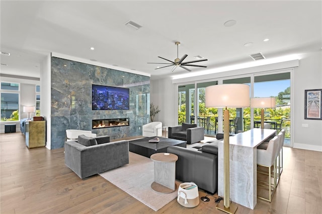 living room featuring ceiling fan, light hardwood / wood-style flooring, and a high end fireplace