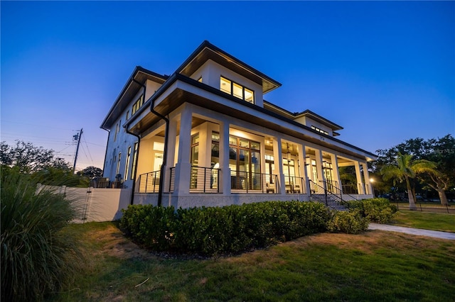 property exterior at dusk featuring a porch and a yard