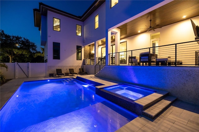 pool at twilight featuring an in ground hot tub, ceiling fan, and a patio area