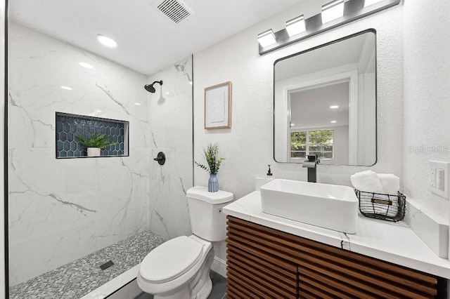 bathroom featuring vanity, toilet, and tiled shower