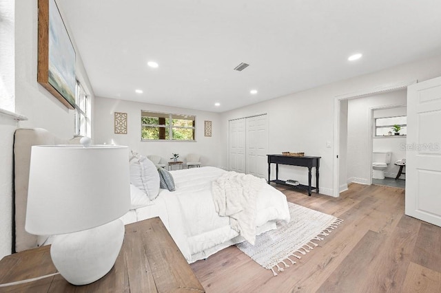 bedroom featuring light hardwood / wood-style floors, ensuite bath, and a closet