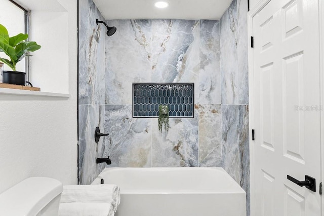 bathroom featuring tiled shower / bath combo and toilet