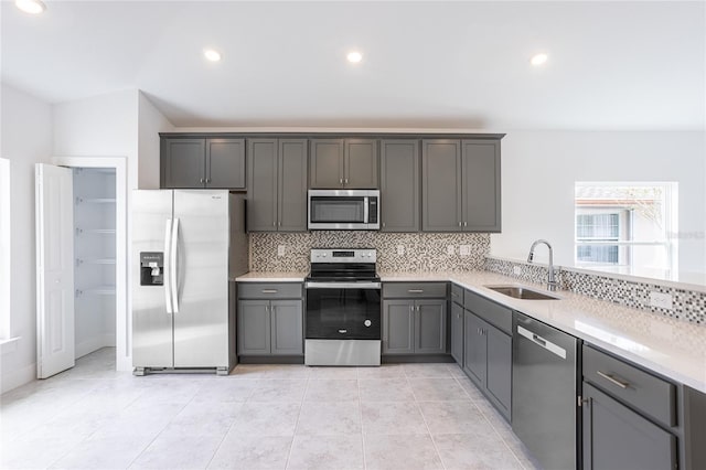 kitchen with gray cabinetry, sink, light tile patterned floors, appliances with stainless steel finishes, and tasteful backsplash