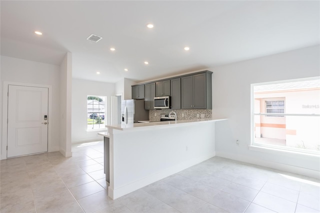 479 Winwood Ct, Port Charlotte, FL 33954 - kitchen featuring appliances with stainless steel finishes, light countertops, decorative backsplash, a peninsula, and light tile patterned flooring