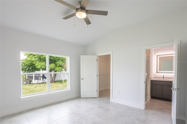 479 Winwood Ct, Port Charlotte, FL 33954 - unfurnished bedroom with vaulted ceiling, a sink, baseboards, a walk in closet, and light tile patterned floors