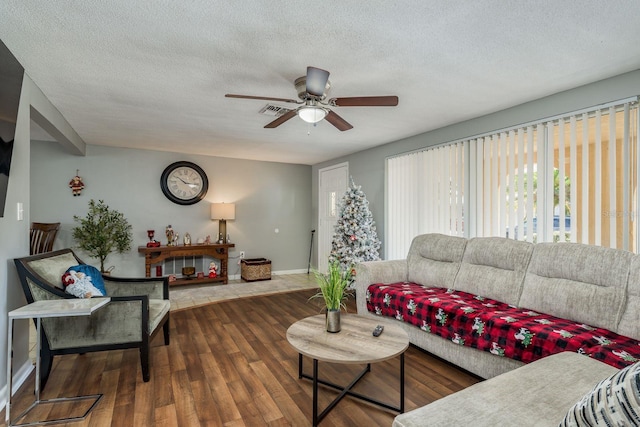 living room featuring ceiling fan, dark hardwood / wood-style flooring, and a textured ceiling