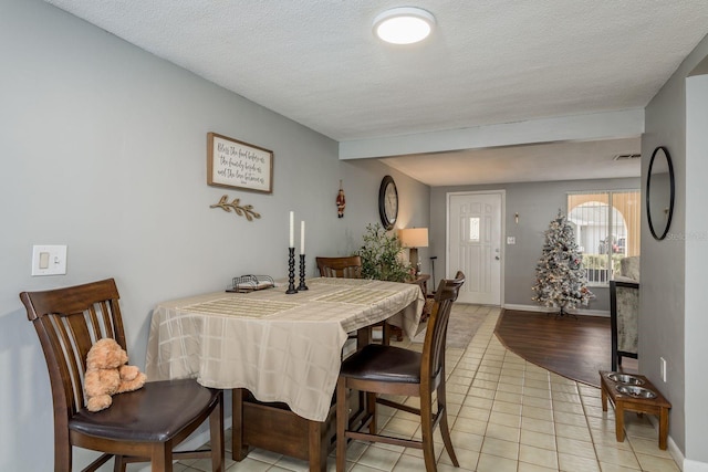 tiled dining space with a textured ceiling