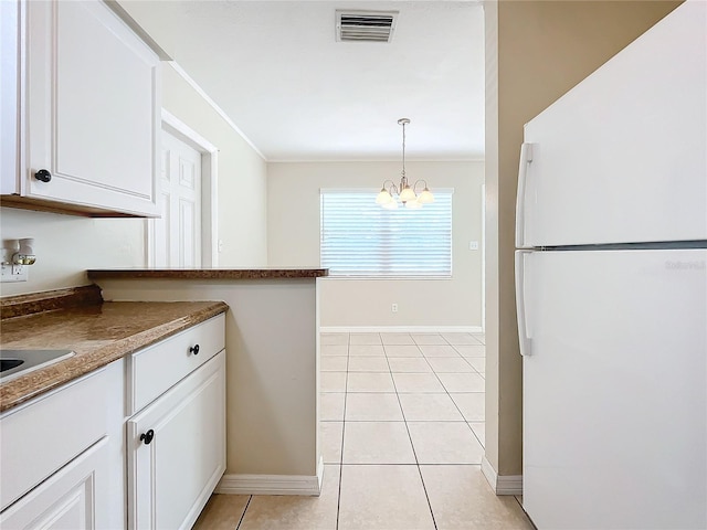 kitchen featuring pendant lighting, a notable chandelier, white refrigerator, and white cabinetry