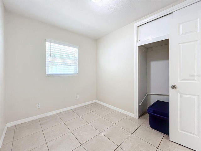 unfurnished bedroom featuring light tile patterned flooring, a textured ceiling, and a closet