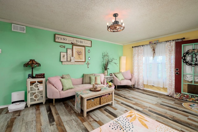 living room featuring crown molding, wood-type flooring, a textured ceiling, and an inviting chandelier