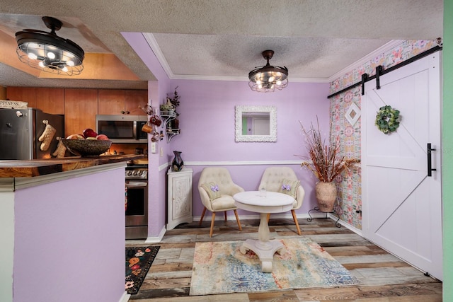 interior space with a barn door, crown molding, light hardwood / wood-style floors, and a textured ceiling