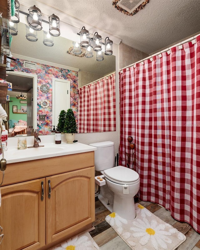 bathroom with a textured ceiling, toilet, hardwood / wood-style flooring, vanity, and ornamental molding