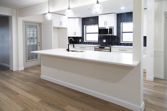 kitchen featuring stainless steel appliances, decorative light fixtures, sink, and white cabinets